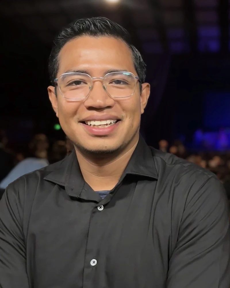Dannieldev, con gafas y camisa negra, sonriendo.